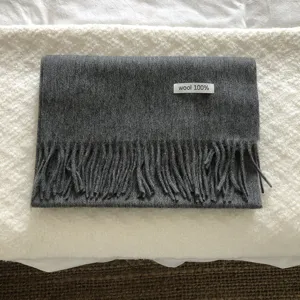 Detalle bufanda invierno de lana gris, textura de flecos acogedora y material suave.