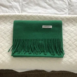 Primer plano detallado de bufanda de lana verde con textura suave y flecos finos.