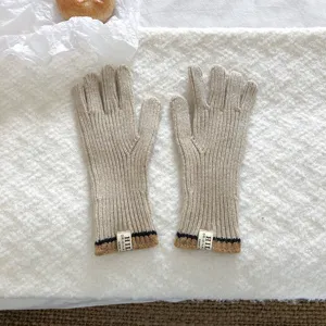 Close-up detail of warm knitted winter gloves featuring stylish ribbed cuffs and chic woven labels.