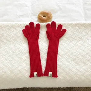 Gedetailleerd overzicht van rode gebreide lange handschoenen met ribbeltextuur en etiket.