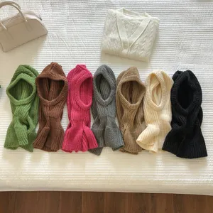 Detailed flatlay of assorted knitted balaclava hats and cardigan sweater in cozy winter style.