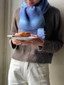 Vista detallada de una suave bufanda de punto con degradado azul, ideal para el invierno.