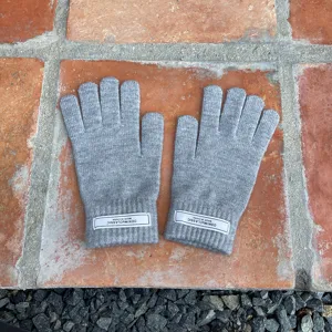 Nahaufnahme von grauen Strick-Winterhandschuhen mit Bündchen-Etikett, warmer Wollstoff.