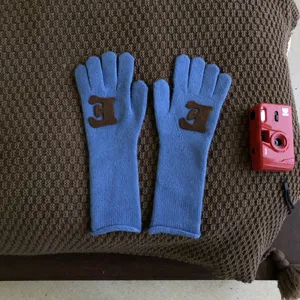 Einfarbige blaue Strickhandschuhe mit braunem Buchstaben Aufnäher für kalte Wintertage.