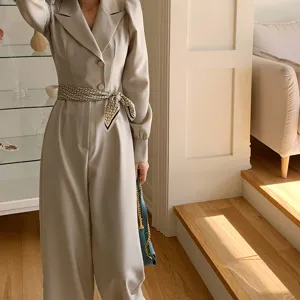 Detail view of stylish beige jumpsuit paired with a luxury patterned silk scarf belt and chic bag.