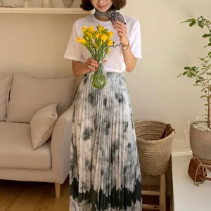 Elegant women's outfit featuring a white t-shirt, tie-dye pleated skirt, and stylish neck scarf.