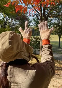 Outdoor detail shot showing comfortable winter color-block knit gloves worn in a park setting.