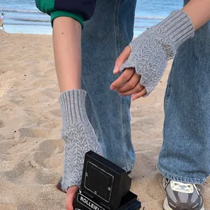 Graue gestrickte fingerlose Handschuhe Detailansicht, warmer Armwärmer mit Wellenmuster.
