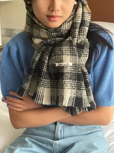 Vue détaillée d'une écharpe à carreaux noir et blanc à franges, chaude et chic en hiver.