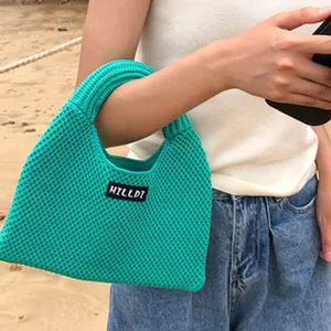 Grüne Strick-Dumpling-Handtasche Detailaufnahme mit weicher Textur und schickem Markenetikett.