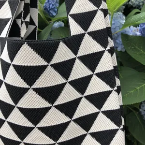 Primo piano della borsa tote in maglia geometrica nera e bianca con trama e motivo morbidi.
