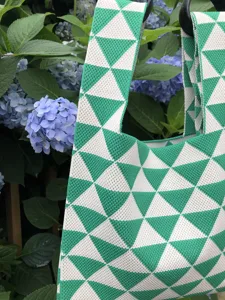 Dettaglio della borsa shopper in maglia geometrica verde e bianca, elegante borsa da donna.