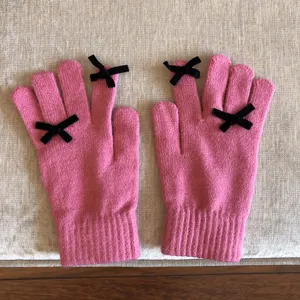 Süße rosa Strickwinterhandschuhe mit schwarzen Schleifendetails, warmes Design für kalte Tage.