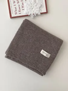 Detailaufnahme eines warmen winterlichen Strickschals in Braunton mit dekorativem Handmade-Etikett.