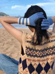 Nahaufnahme von kuscheligen gestreiften Touchscreen-Strickhandschuhen im Freien im Herbst.