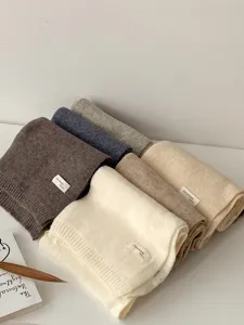 Detailansicht gestapelter, dicker und warmer Winterstrickschals in verschiedenen neutralen Farben.
