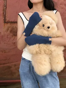 Comodi guanti invernali in maglia blu senza dita abbinati a un morbido orsetto di peluche.