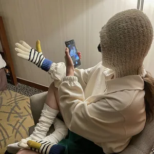 Nahaufnahme von kuscheligen Winter-Strickhandschuhen mit gelben Daumen und blauen Bündchen.