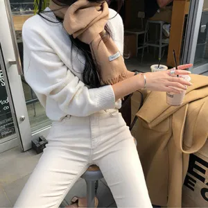 Cómoda bufanda de lana con flecos combinada con jersey blanco para estilo otoñal.