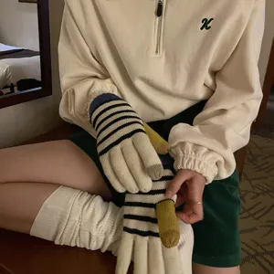 Detailaufnahme von retro gestreiften Strickwinterhandschuhen mit kontrastierenden Fingerspitzen.