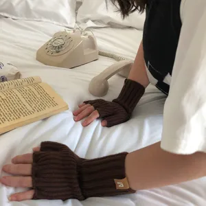 detalle de guantes sin dedos de punto marron con textura de invierno y pequena etiqueta de logotipo