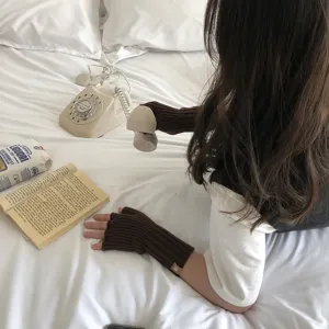 Vista detallada de guantes de punto marrón sin dedos que muestran una textura acanalada.