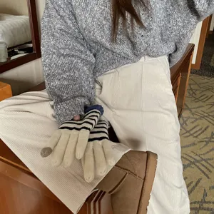 Detailansicht von warmen gestreiften Strick-Touchscreen-Handschuhen im gemütlichen Winterstil.