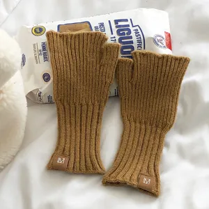 Primer plano detallado de guantes de invierno de punto sin dedos en amarillo mostaza con puños.