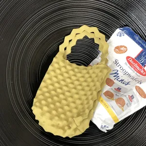 Detailopname van een gele mini gebreide handtas met popcorntextuur op een zwart bord.