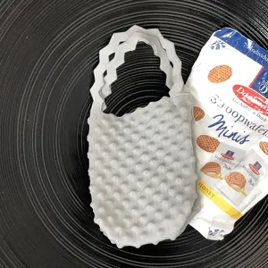 Grijze gebreide mini handtas detail met unieke bubbeltextuur en stijlvol golvend handvat.