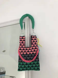 Detailed view of the gradient heart knit handbag featuring a chunky chain and green handle.