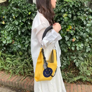 Gelbe Strick-Handtasche Detail mit blauem Smiley-Gesicht Muster und stilvollem Kettenriemen.