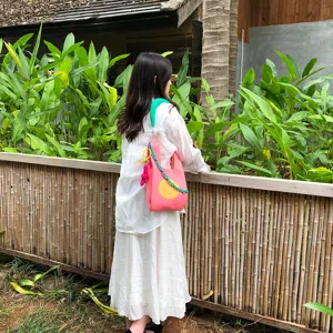Outdoor-Lifestyle-Detailansicht der pinken Strickhandtasche mit Smiley-Gesicht und Kettengurt.