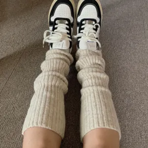 Detailshot van gezellige gebreide beenwarmers gedragen met stijlvolle sneakers, wintermode.