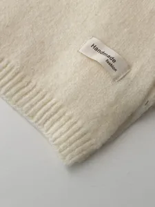 Nahaufnahme der Textur des beige winterlichen Strickschals, weiches warmes Detailbild.