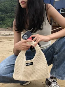 Detailaufnahme der eleganten gestrickten Handtasche mit dem gewebten Markenetikett.