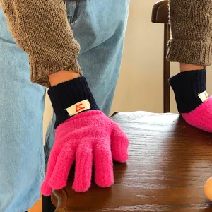 Detailopname van winterse dikke pluche warme gebreide handschoenen in roze met marineblauwe boorden.