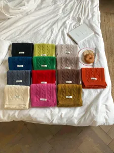 Detaillierte Ansicht kuscheliger Strickschals in bunten Farben ordentlich auf dem Bett.