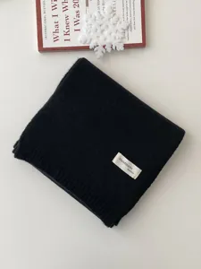 Nahaufnahme eines ordentlich gefalteten schwarzen Strickschals mit handgemachtem Label.