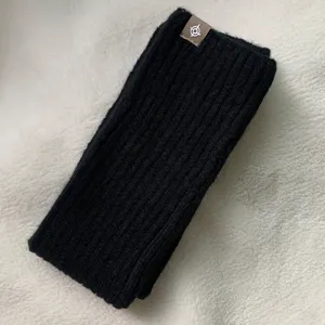 Detailopname van zwarte geribbelde gebreide beenwarmers, knus wintermode-accessoire.