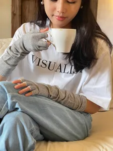 Vue détaillée de chauffe-bras tricotés gris sans doigts portés par un modèle dans un cadre chaleureux.
