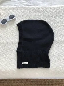 Vue détaillée de la cagoule en tricot 100% laine noire, avec étiquette et texture douce.