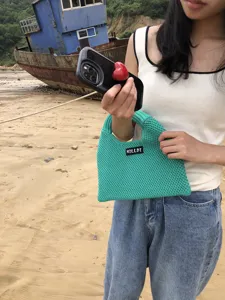 Detailansicht der grünen Strickhandtasche draußen am Strand, Textur und Design zeigend.