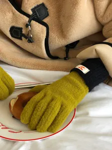 Gedetailleerd close-up van gezellige gele winter gebreide handschoenen met zwarte boorden.