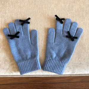 Graue blaue Strickhandschuhe Detailansicht, süße Winterhandschuhe mit schwarzer Schleife.