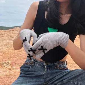 Gemütliche graue Strickhandschuhe mit niedlichen schwarzen Schleifen, warm für den Winter.