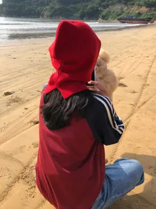 Vue détaillée d'une cagoule en tricot rouge sur la plage, vêtement d'hiver chaud et doux.