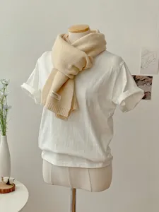 Nahaufnahme Detail des beigen Strickschals an Puppe, weicher warmer Winterhalswärmer.