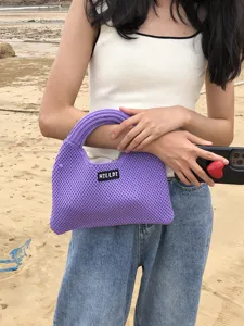 Detailaufnahme einer stilvollen, prachtvollen gehäkelten Handtasche am Strand gezeigt.