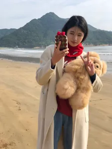 Vue détaillée du bonnet cagoule en tricot de laine rouge porté sur une plage en extérieur.